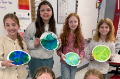 students holding earth day art projects