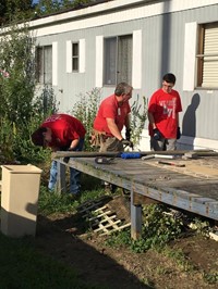 c v students and ramp it up coordinator work on removing old boards from deck