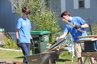 two males lifting pallets of wood