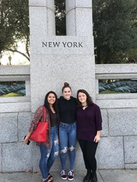 students in front of statue that reads new york