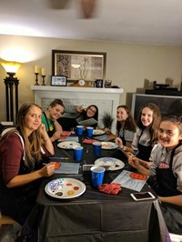 students smile painting pumpkin pictures inside of house