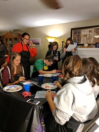 students paint pumpkin pictures inside of house