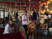 more students smiling riding carousel