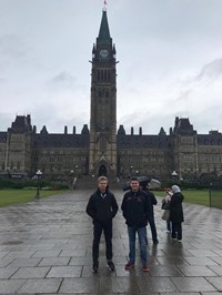 two male students smile in front of building