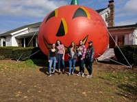 students stand in front of inflatable pumpkin.