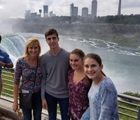 group of four people pose in front of niagra falls