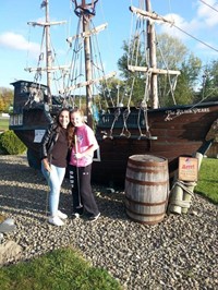 students smile in front of pirate ship