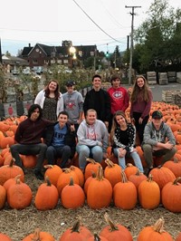 students at the cider mill sitting on pumpkins