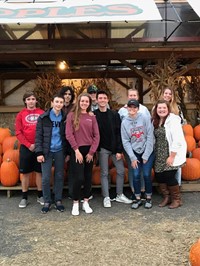 group of students standing in front of pumpkins