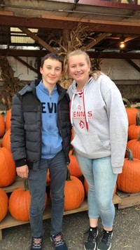two students standing in front of pumpkins