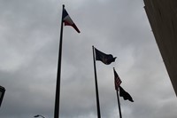 french flag waves with other flags in downtown binghamton outside of city hall
