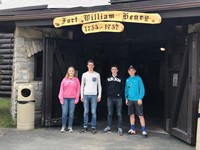 students under sign that reads fort william henry