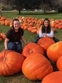 students smile next to large pumpkins