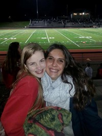 two female students smile at football game