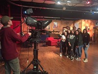 students pose in front of broadcast camera at w s k g