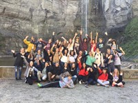 group of students wave at water falls