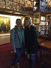 two female students pose in a library
