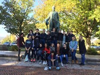 students pose with a statue