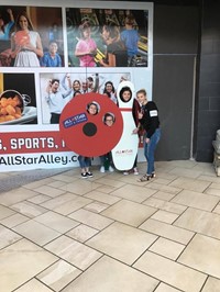 students pose inside of bowling pin and ball cut outs