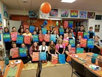 students hold up paintings of trees with their american counterparts