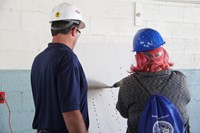 female student tests drill equipment during construction career day