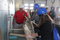 two female students take on carpentry challenge of seeing who can hammer a nail into ply of wood qui