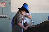 student tries out roofing on a sample roof with hammer and nail