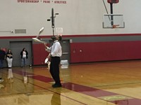 mister stafford juggling with a unicycle balancing on his face at pep rally