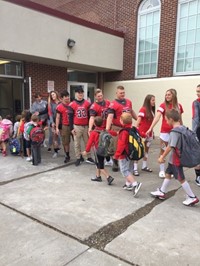 student athletes give port dickinson elementary students a high five as they enter the school buildi