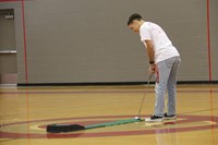 high school golf team member does a putting challenge during high school pep rally