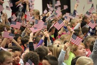 students sitting waving american flags in the air