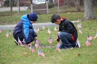 two boys planting american flags in grass