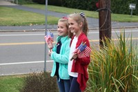 two students smile holding flags