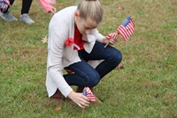 student plants american flag in grass