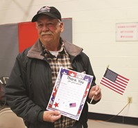 veteran holding up thank you card and flag