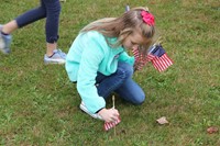 student plants flag in grass