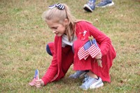 girl planting flag in grass