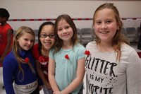 four girls smile wearing red poppies in recognition of veterans