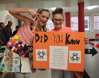 students dressed in recyclable items and holding sign to raise awareness for recycling