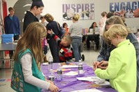 girl scout table helping students make popsicle harmonicas