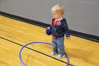 little boy hula hoops while wearing a ball