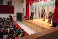 students sitting observing fire fighters on stage