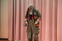firefighter demonstrates putting on his equipment