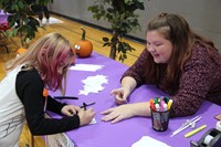 student helping younger student with activity at humanities night