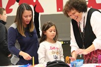 teacher helping student and parent at humanities night table