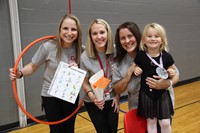 three teachers and student smile at olympics activity at humanities night