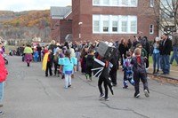 students walking in a parade in front of crowd of families