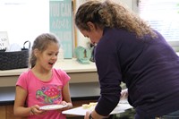 woman holds plate of cheese for girl