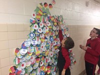 students putting holiday ornament on wall