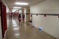 students play with dash robots in the hallway